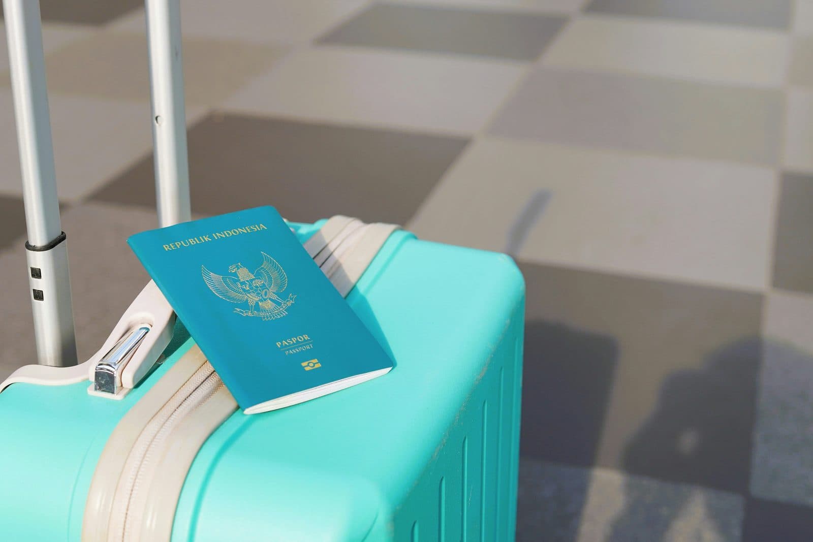 A passport resting on a turquoise suitcase